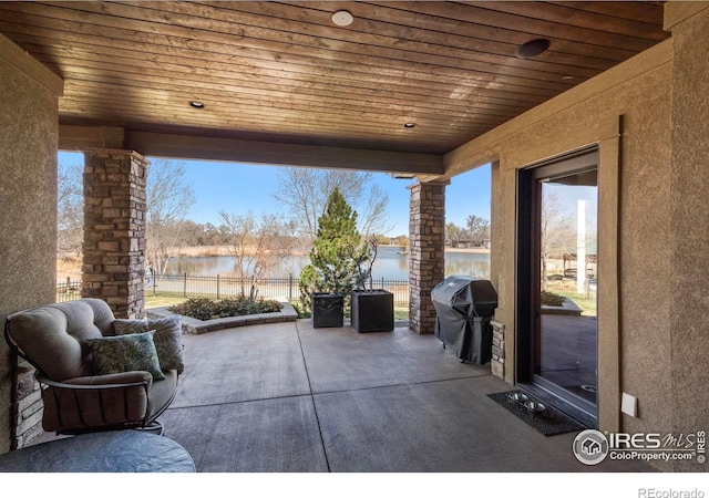 view of patio / terrace with a water view, a grill, and fence