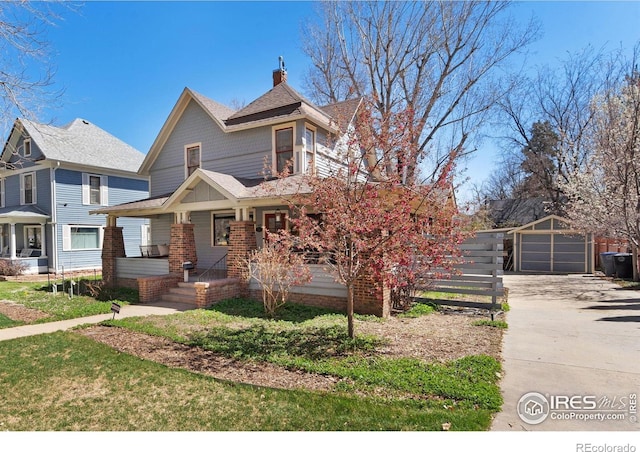 victorian home featuring a porch, a garage, an outdoor structure, concrete driveway, and roof with shingles