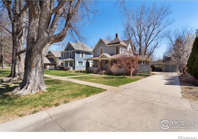 victorian house with a front yard, an outbuilding, a garage, and a chimney