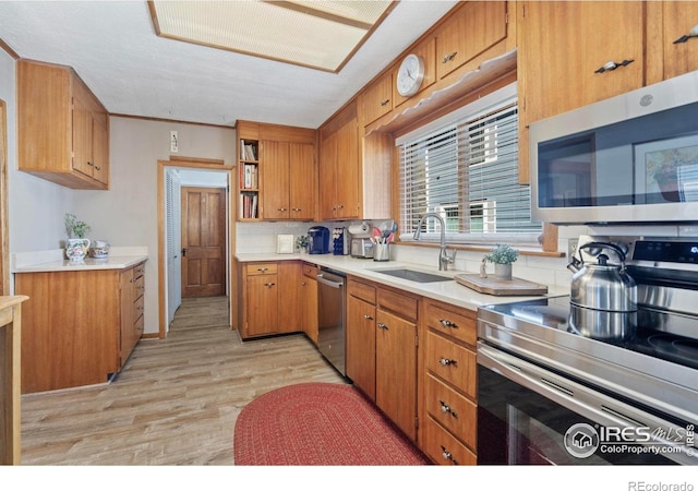 kitchen featuring stainless steel appliances, light wood-style floors, brown cabinets, and a sink