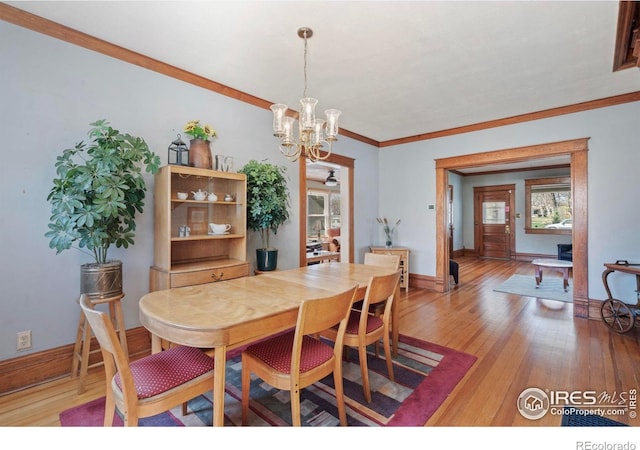 dining room featuring crown molding, light wood-style flooring, a chandelier, and baseboards