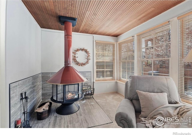 sitting room featuring wooden ceiling, a wood stove, and carpet