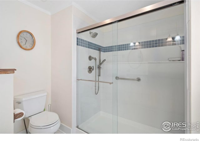 bathroom featuring crown molding, toilet, a shower stall, and baseboards