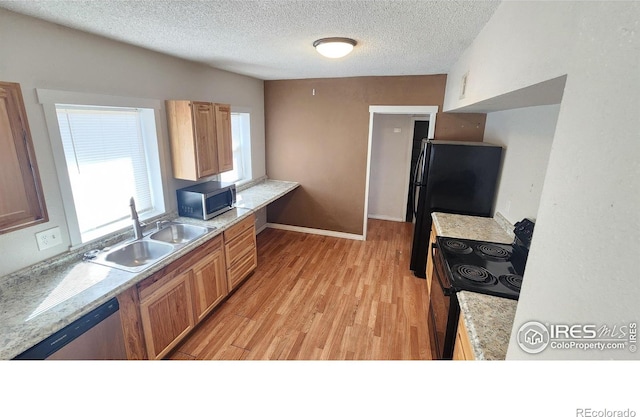 111 N 8th Ave, Sterling, CO 80751 - kitchen featuring stainless steel appliances, light wood finished floors, a textured ceiling, and a sink