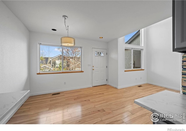 unfurnished dining area with light wood finished floors, baseboards, and visible vents
