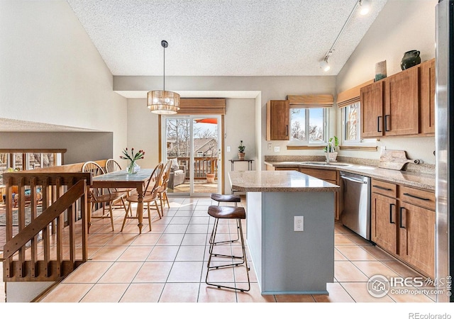 kitchen featuring light tile patterned floors, rail lighting, a center island, dishwasher, and a sink