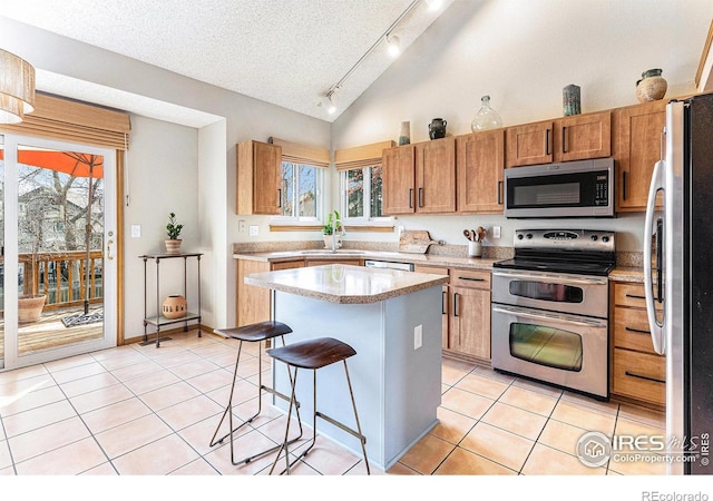 kitchen featuring a sink, light countertops, appliances with stainless steel finishes, light tile patterned flooring, and a breakfast bar area