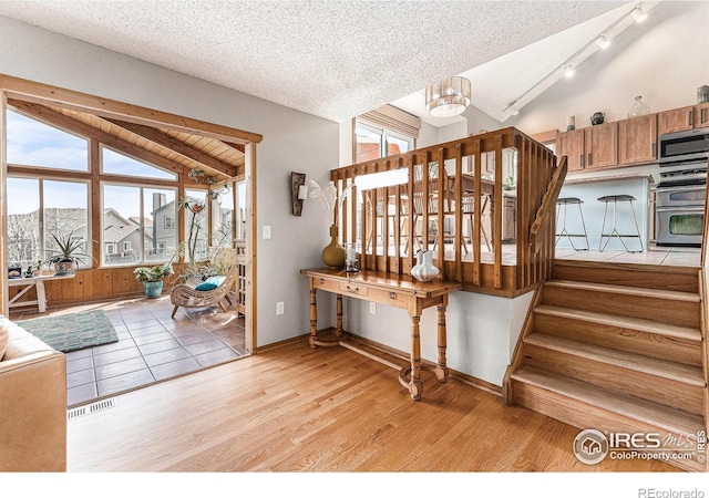 staircase featuring wood finished floors, visible vents, lofted ceiling, and plenty of natural light