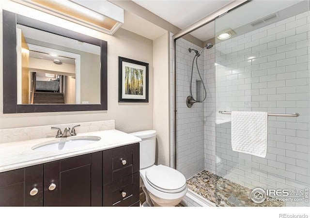 bathroom with toilet, vanity, a shower stall, and visible vents
