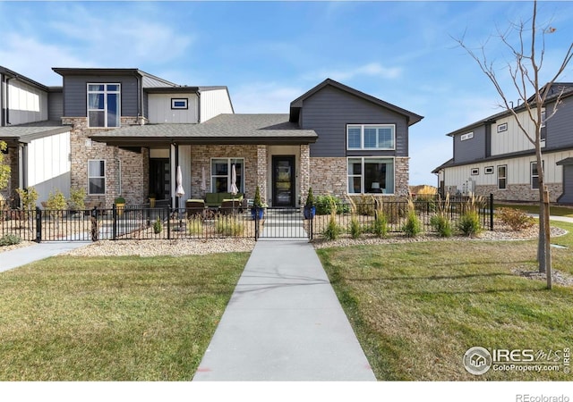 view of front of home with a front lawn, a shingled roof, stone siding, and a fenced front yard