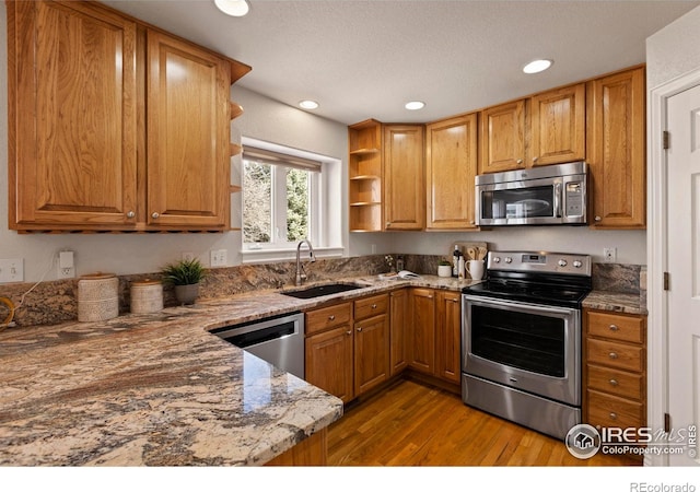 4748 Westbury Dr, Fort Collins, CO 80526 - kitchen featuring stone countertops, open shelves, appliances with stainless steel finishes, a sink, and wood finished floors