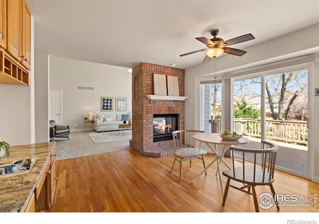 4748 Westbury Dr, Fort Collins, CO 80526 - dining room with visible vents, baseboards, a brick fireplace, a ceiling fan, and light wood finished floors