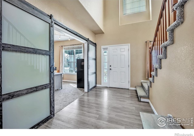 foyer with wood finished floors, baseboards, a barn door, and stairs