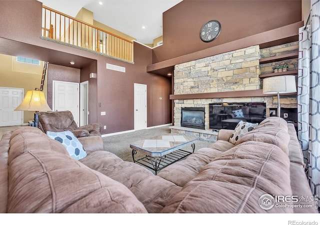 carpeted living area featuring a high ceiling, baseboards, a stone fireplace, and visible vents