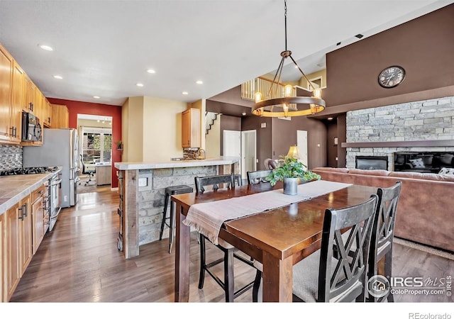 dining room with a chandelier, a fireplace, recessed lighting, and wood finished floors