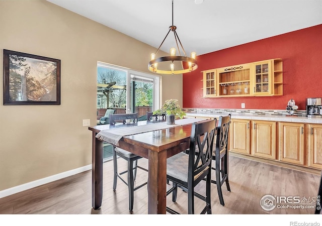 dining room featuring baseboards, light wood finished floors, and a notable chandelier