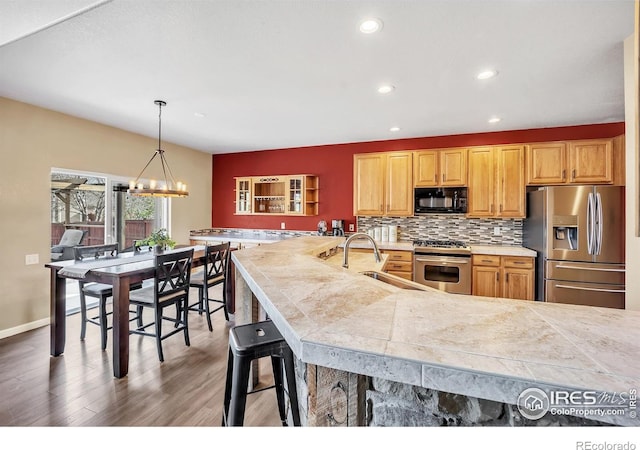 kitchen featuring tasteful backsplash, recessed lighting, appliances with stainless steel finishes, a sink, and wood finished floors
