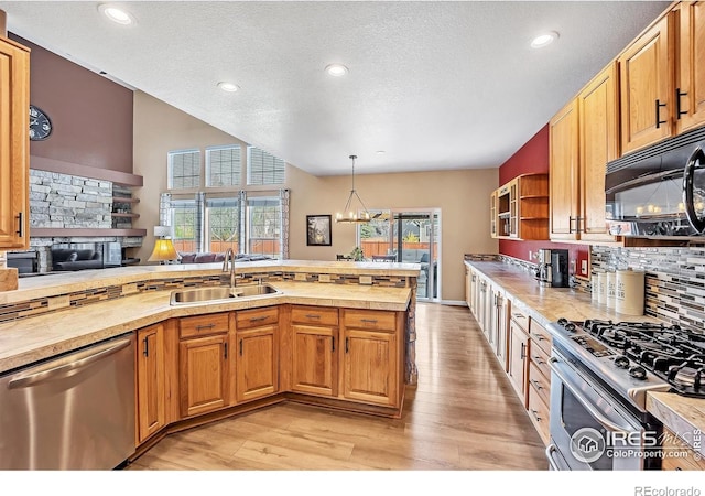 kitchen with light wood-style floors, appliances with stainless steel finishes, light countertops, a sink, and decorative backsplash