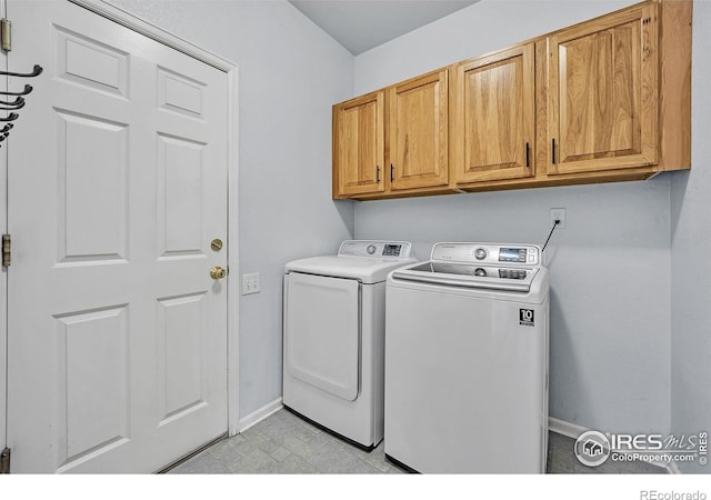 laundry area featuring washing machine and clothes dryer, baseboards, and cabinet space