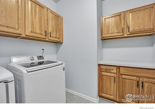 laundry area with washing machine and dryer, baseboards, and cabinet space
