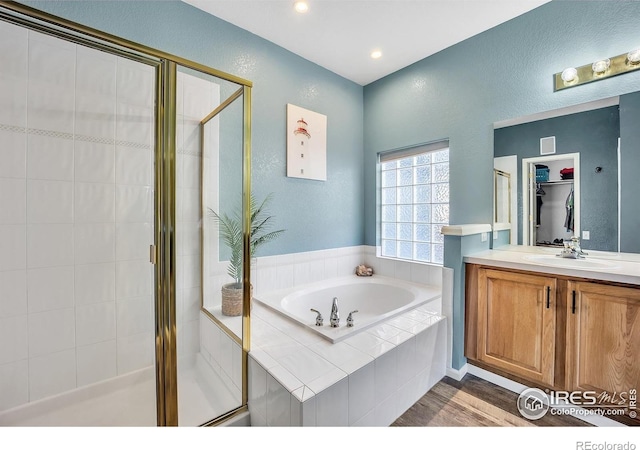 full bathroom with a stall shower, a garden tub, vanity, and wood finished floors