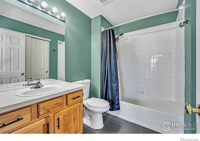 full bathroom with vanity, a textured wall, tile patterned floors, shower / bath combination with curtain, and toilet