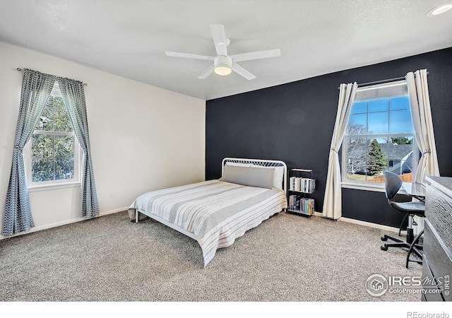 carpeted bedroom featuring baseboards, multiple windows, and a ceiling fan