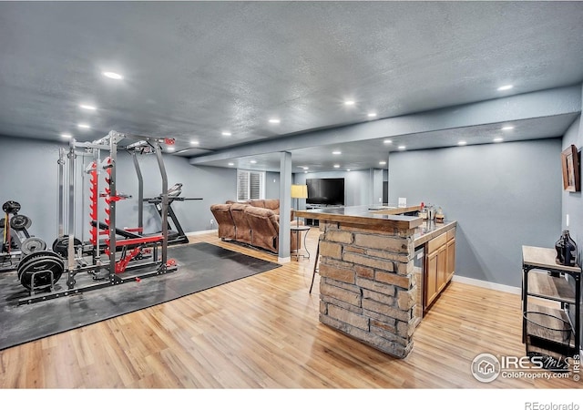 workout room featuring baseboards, light wood-type flooring, and recessed lighting