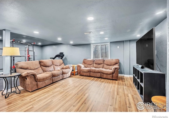 living area with a textured ceiling, wood finished floors, visible vents, and recessed lighting