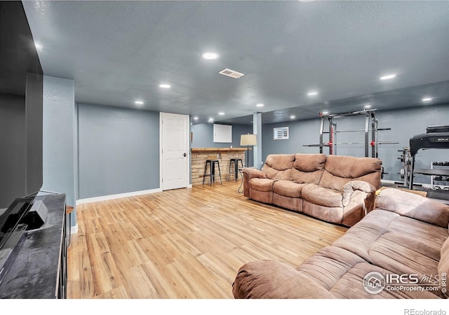 living area featuring a textured ceiling, visible vents, recessed lighting, wood finished floors, and baseboards