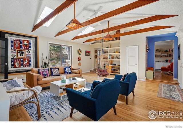 living area featuring light wood-type flooring, baseboards, and lofted ceiling with skylight