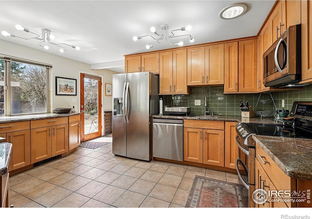 kitchen with tasteful backsplash, light tile patterned flooring, brown cabinets, stainless steel appliances, and a sink