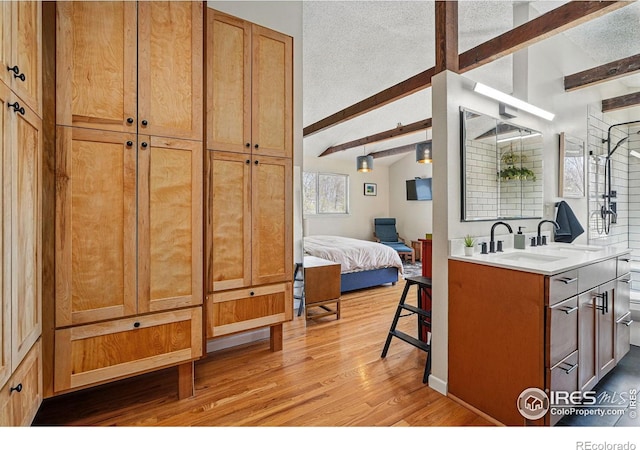interior space featuring light wood-style floors, light countertops, a sink, and lofted ceiling with beams