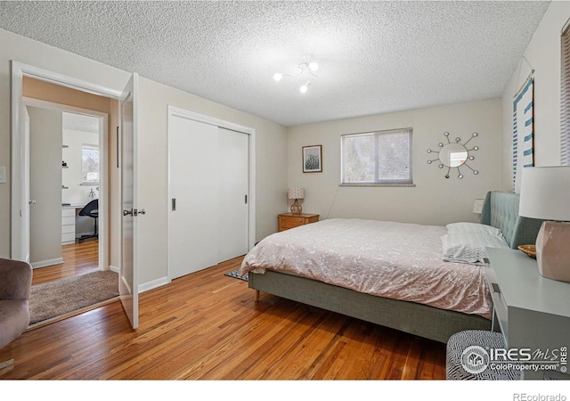 bedroom featuring a textured ceiling, wood finished floors, and a closet