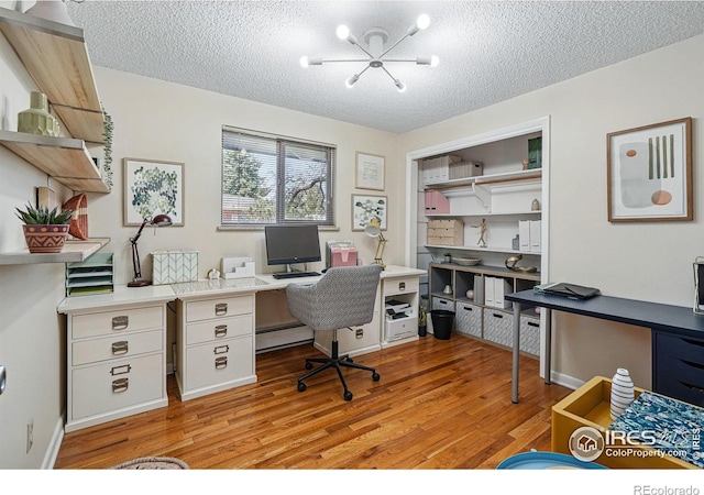 office featuring a baseboard heating unit, baseboards, an inviting chandelier, a textured ceiling, and light wood-style floors