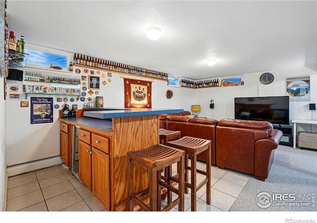 bar featuring a dry bar, a baseboard radiator, light tile patterned flooring, and a textured ceiling