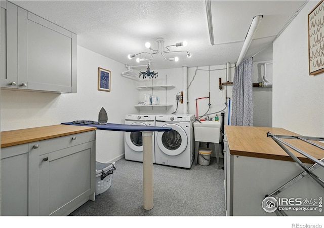 laundry area featuring washer and dryer, a textured ceiling, a sink, and cabinet space