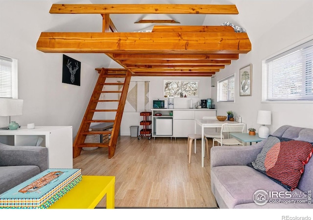 living area featuring wood finished floors, vaulted ceiling with beams, and a wealth of natural light