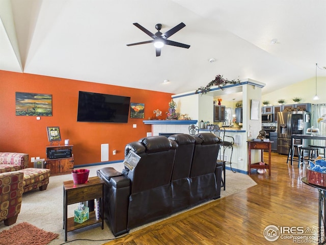 living room with a ceiling fan, wood finished floors, and vaulted ceiling