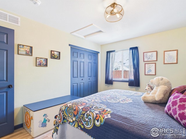 bedroom with visible vents, attic access, wood finished floors, and a closet