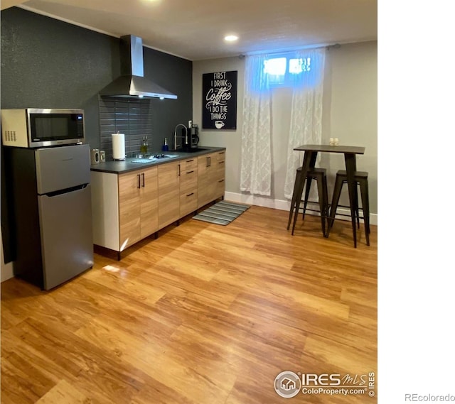 7170 Zuni St, Denver, CO 80221 - kitchen with baseboards, wall chimney range hood, light wood-style flooring, dark countertops, and stainless steel appliances