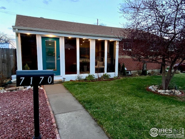 7170 Zuni St, Denver, CO 80221 - view of front of property featuring fence, a front yard, a sunroom, and a shingled roof