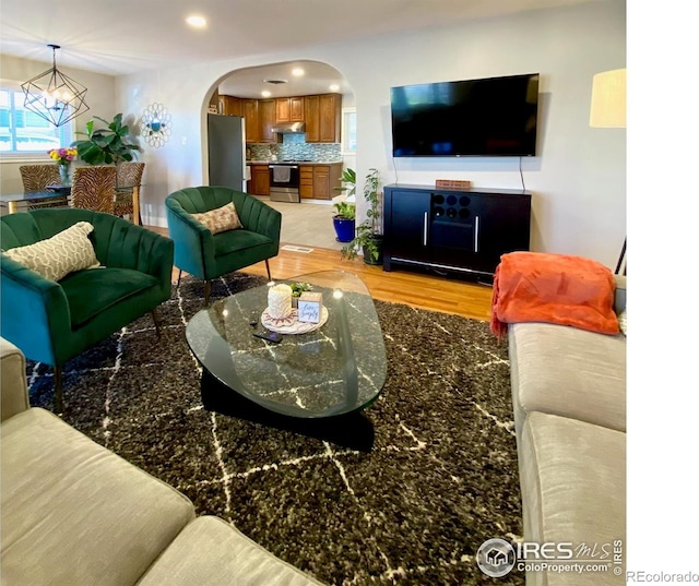 7170 Zuni St, Denver, CO 80221 - living room with baseboards, arched walkways, an inviting chandelier, recessed lighting, and light wood-style flooring