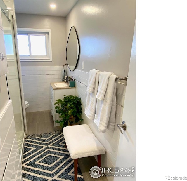7170 Zuni St, Denver, CO 80221 - bathroom with vanity, recessed lighting, toilet, wainscoting, and tile walls