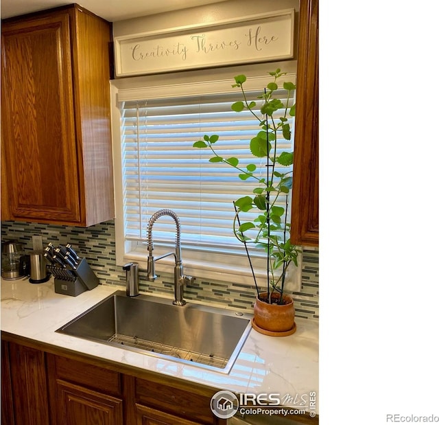 7170 Zuni St, Denver, CO 80221 - kitchen featuring a sink, brown cabinetry, and decorative backsplash