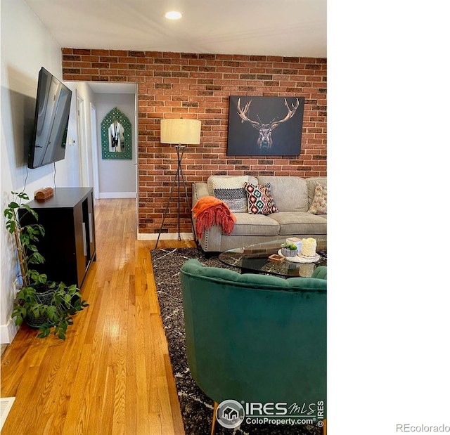 7170 Zuni St, Denver, CO 80221 - living room featuring baseboards, light wood-type flooring, and brick wall