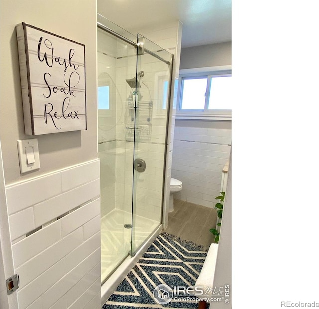 7170 Zuni St, Denver, CO 80221 - full bathroom with a shower stall, wainscoting, tile walls, and toilet