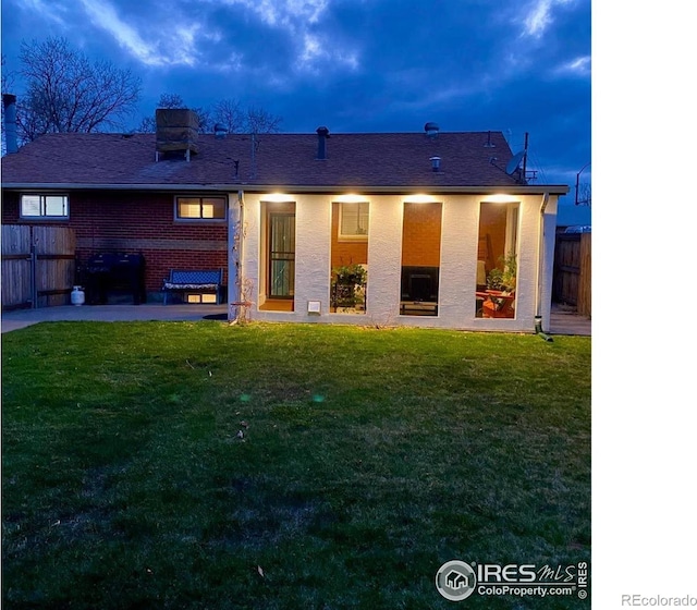 7170 Zuni St, Denver, CO 80221 - back of property featuring brick siding, fence, a patio area, and a lawn