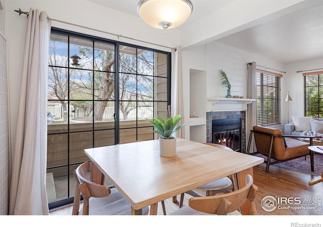 dining space with a tile fireplace and wood finished floors