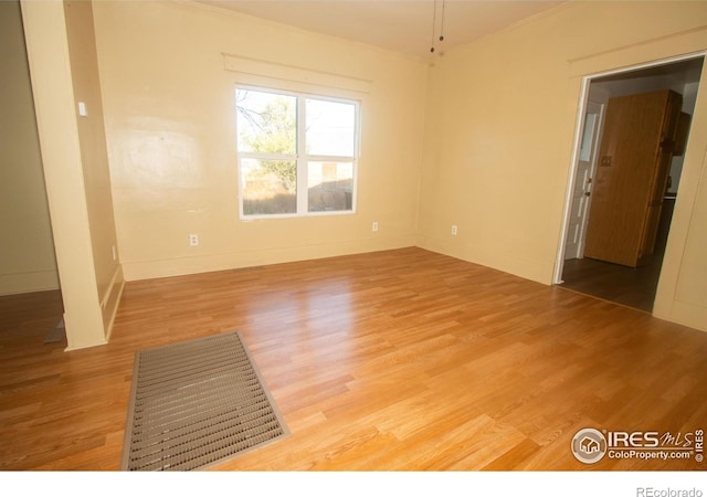 unfurnished room with crown molding, baseboards, and light wood-style floors